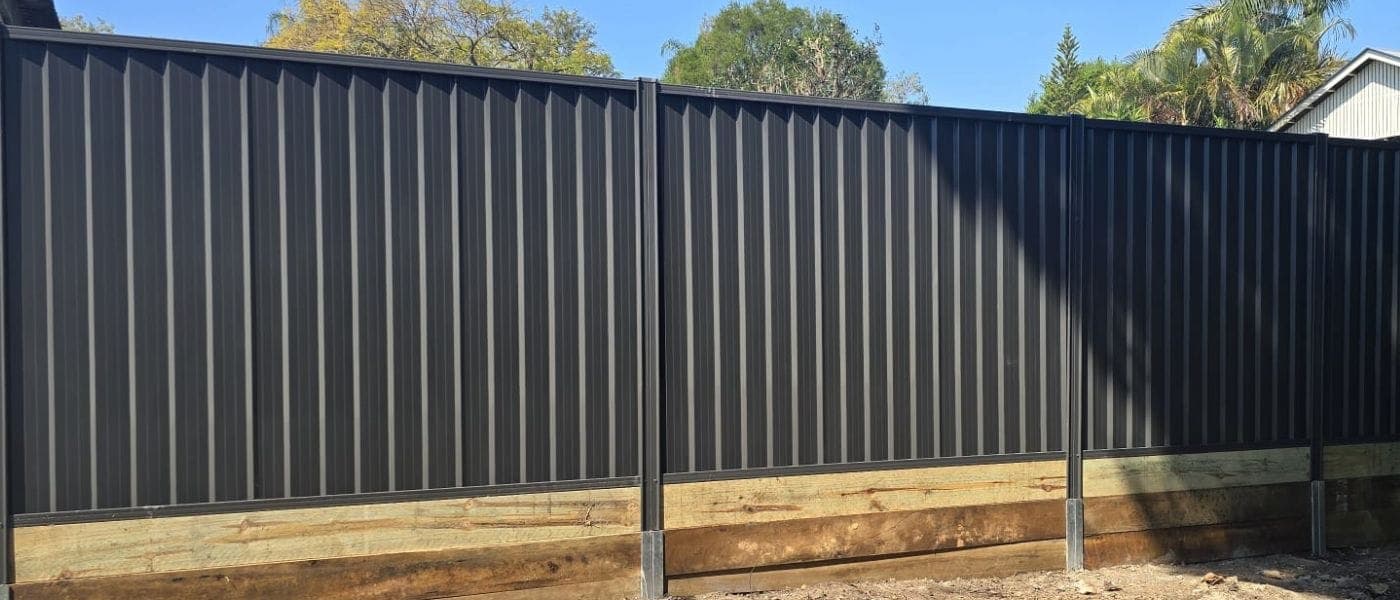 A charcoal Colorbond fence on a timber sleeper base, installed by Inspired Fencing Solutions